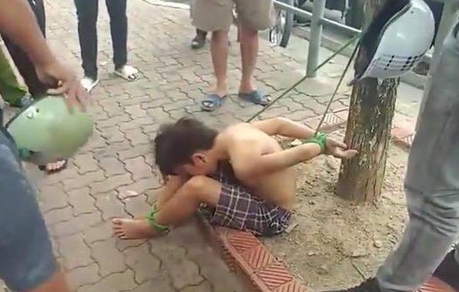 Xôn xao hình ảnh bé trai cởi trần bị trói chân, tay vào gốc cây giữa phố ở Hà Nội