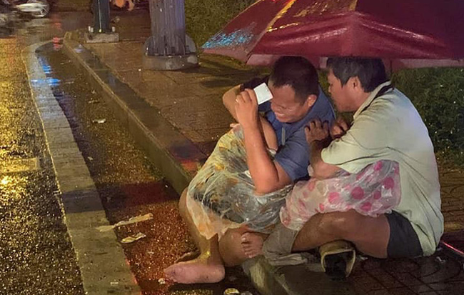 Xót xa hình ảnh 2 người đàn ông khiếm thị che chung chiếc ô dưới cơn mưa Sài Gòn để bán từng chiếc vé số