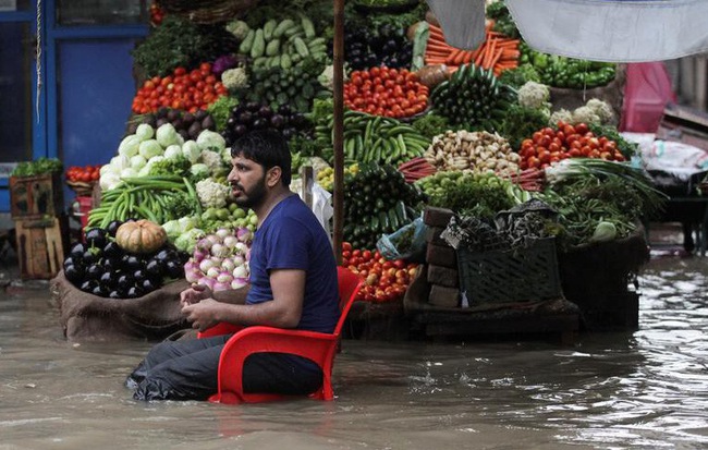 24h qua ảnh: Người đàn ông ngồi bán rau trên dòng nước đục ngầu do lụt lội